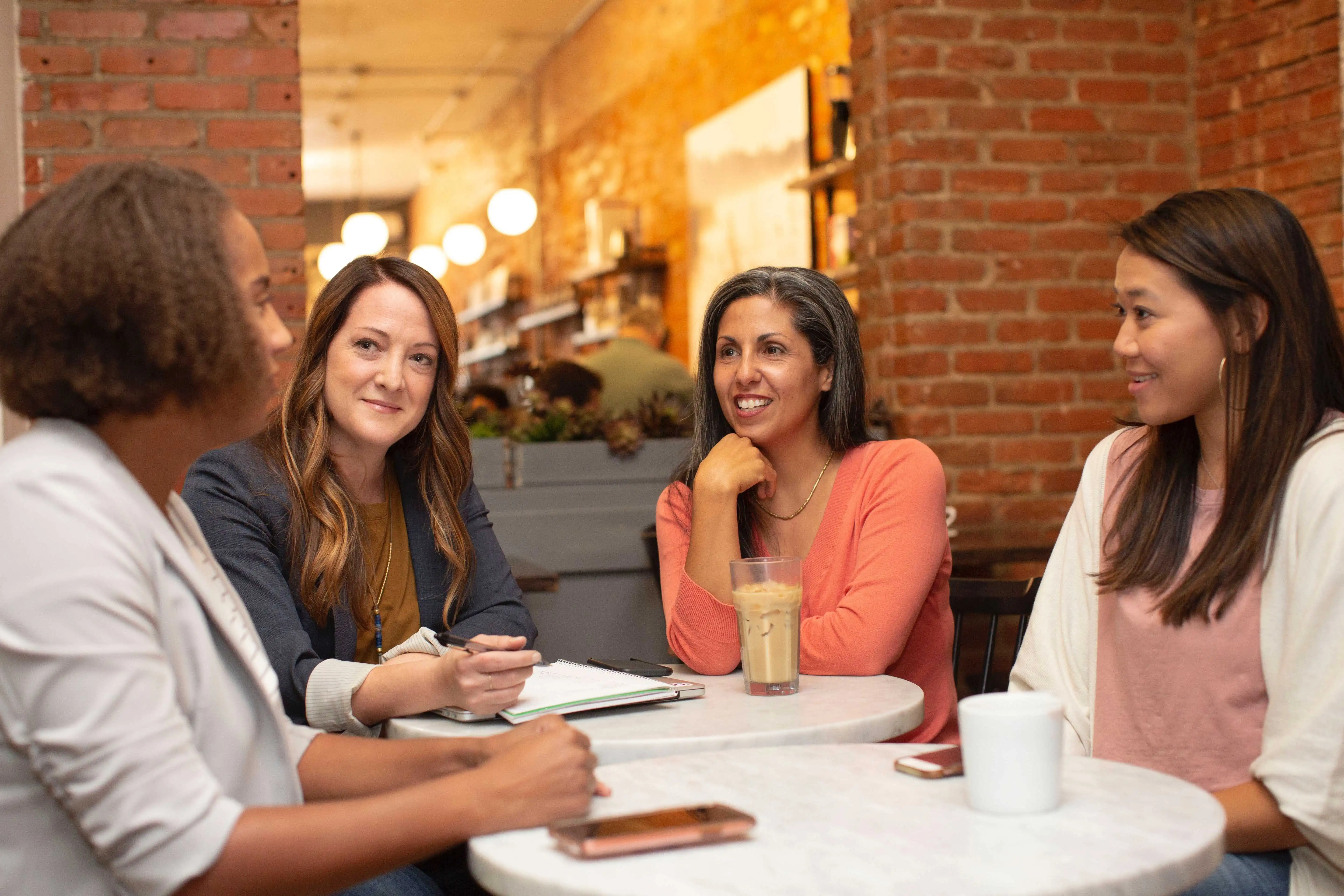 four women conversing around a table