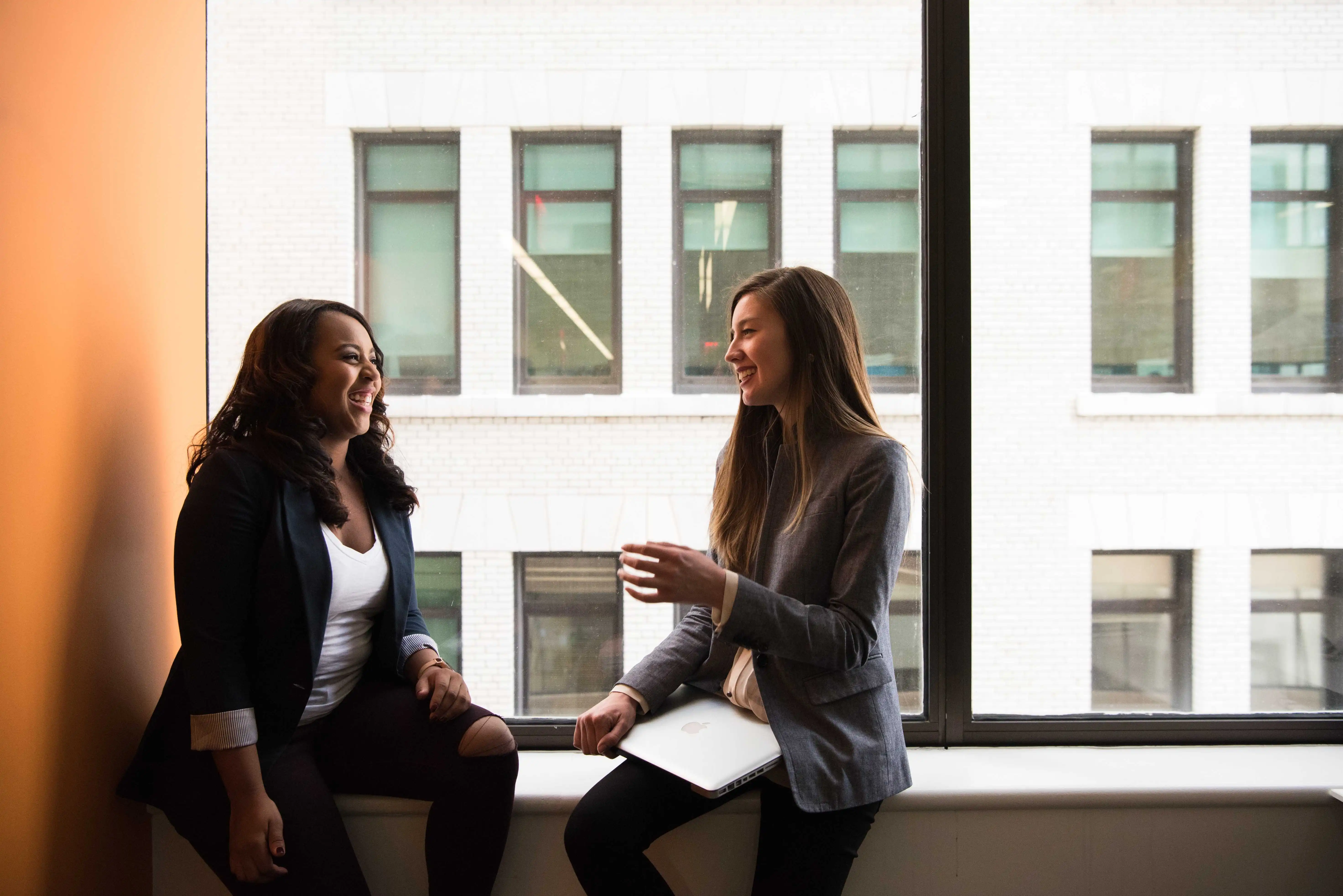 two work colleagues conversing by an office window